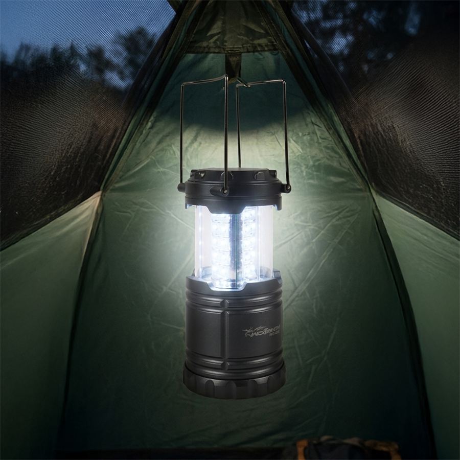 Collapsible LED camping lantern lit inside a green tent at dusk