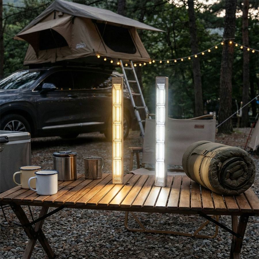 Two LED bar lights standing on a wooden roll table at a campsite in the evening