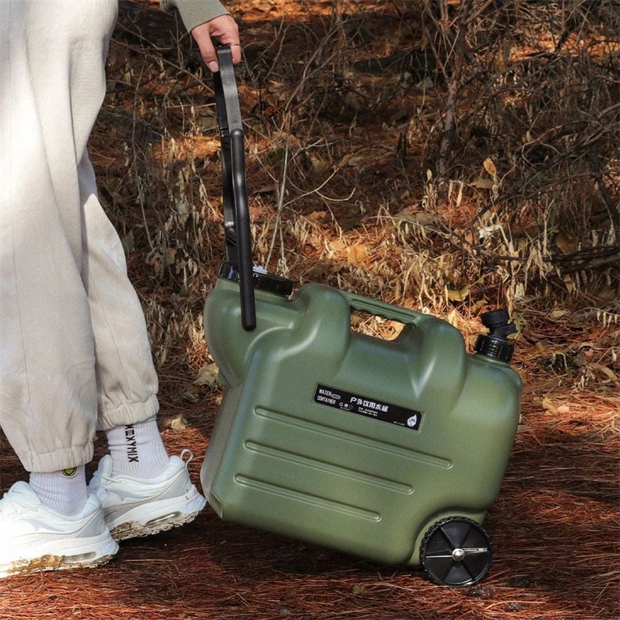 Olive green wheeled outdoor water container being pulled along a forest trail